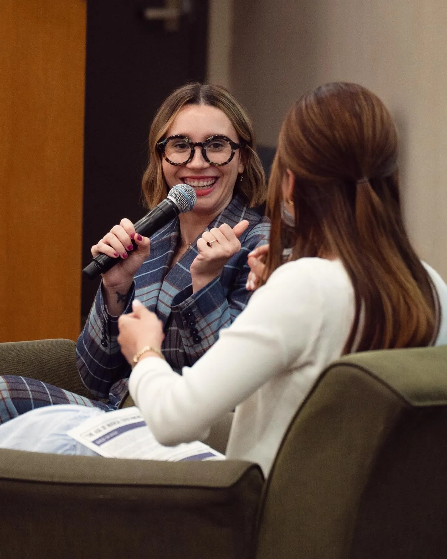 Amanda Montell laughing into a microphone during an onstage conversation